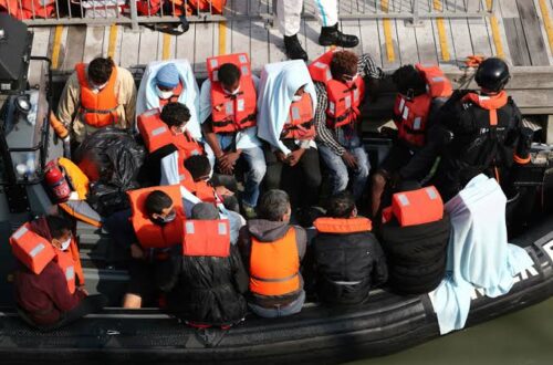 Migrants portant des gilets de sauvetage à bord d'une embarcation gonflable secourue en mer