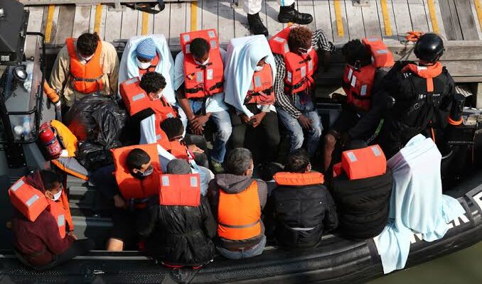 Migrants portant des gilets de sauvetage à bord d'une embarcation gonflable secourue en mer